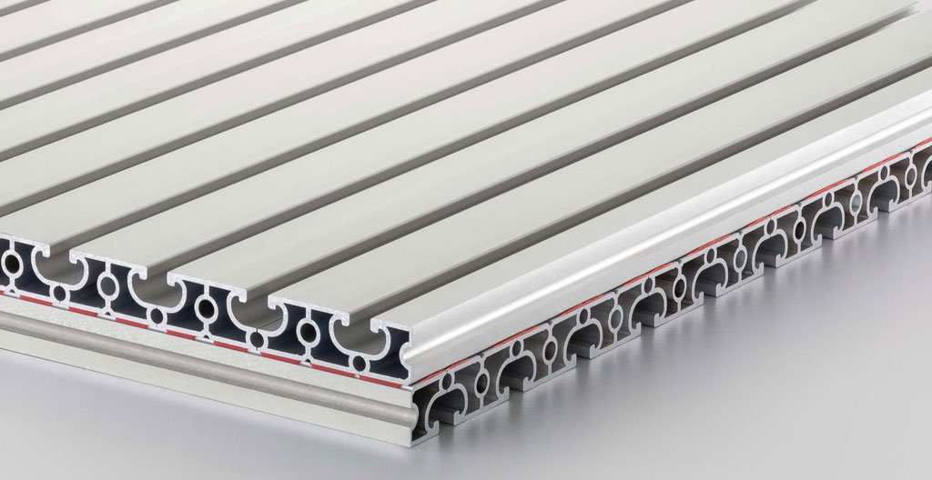 Mains d'un installateur emboîtant une lame de clôture aluminium gris anthracite par le haut dans la rainure verticale d'un poteau, arrière-plan de jardin avec panneaux déjà installés